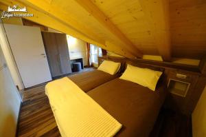 ein großes Bett in einem Zimmer mit Holzdecke in der Unterkunft Alpen Flower esclusivi vicino alle piste da sci in Livigno