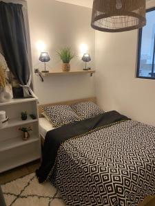 a bedroom with a bed with a black and white comforter at Paradis les pieds sur le sable trouville palace in Trouville-sur-Mer