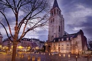 a large church with a clock tower in a city at Bail mobilité appartement Louvre Palais Royal in Paris