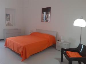 1 dormitorio con 1 cama de color naranja y 1 silla en HAPPY HOUSE Salento Apartment, en Brindisi