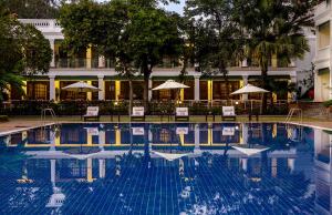 a swimming pool with chairs and umbrellas next to a building at Jehan Numa Palace Hotel in Bhopal
