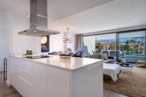 a kitchen with white cabinets and a living room at Holiday Apartment Navigolf La Cala in La Cala de Mijas