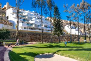 people playing golf in a park in front of a building at Holiday Apartment Navigolf La Cala in La Cala de Mijas