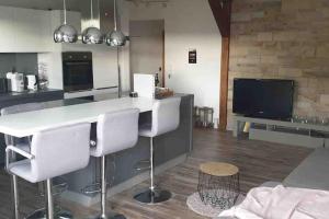 a kitchen with a bar with white chairs and a tv at Bochum ich komm aus Dir! in Bochum +6 photos