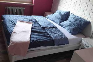 un letto con lenzuola e cuscini blu e bianchi di Bochum ich komm aus Dir! a Bochum