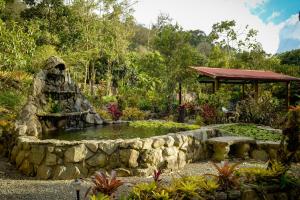 a garden with a pond and a stone wall at Talamanca Nature Reserve in Rivas