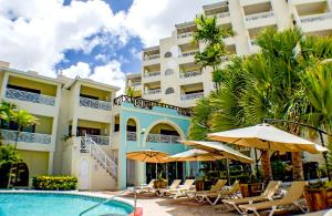 un complejo con piscina, sillas y sombrillas en Barbados Beach Club Resort - All Inclusive, en Christ Church