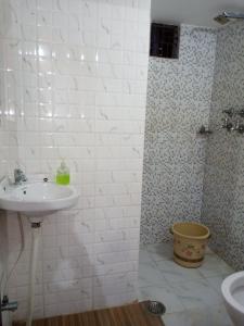 a white bathroom with a sink and a shower at Bliss Guest House Assi Ghat in Varanasi