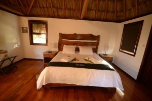 a bedroom with a bed with white sheets and wooden floors at El Ben Cabañas in Caye Caulker +66 photos