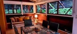a living room with a table and chairs and windows at Bungalow et Duplex de Island Bay in Bouillante