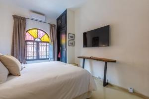 1 dormitorio con 1 cama y TV en la pared en "LE 21", EXCLUSIVE DUPLEX 400m from Jemaa el Fna - JACUZZI - HAMMAM - NETFLIX - HIGH-SPEED WIFI, en Marrakech
