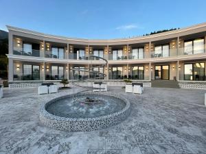 a large building with a fountain in front of it at EBBI HOTEL in Dhërmi