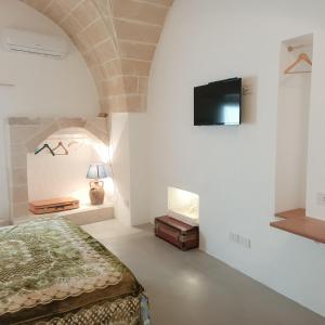a bedroom with a bed and a tv on the wall at Antica Dimora Salentina in Leverano