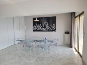 uma sala de jantar com uma mesa de vidro e cadeiras em CANNES Superbe appartement vue mer panoramique em Cannes