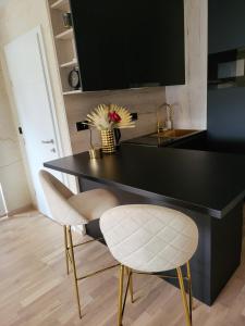 a kitchen with a black counter and two white chairs at Apartman Stari Toranj II in Vukovar