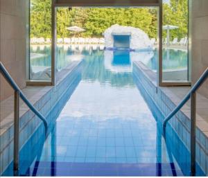 a swimming pool with a blue tile floor and windows at Beatrix Apartments in Bük
