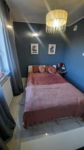 une chambre avec un grand lit recouvert d'une couverture rouge dans l'établissement Apartament Słoneczny, à Dziwnówek