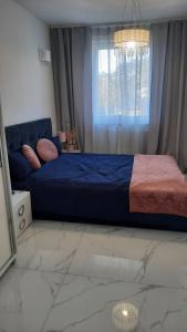 une chambre avec un lit bleu et une fenêtre dans l'établissement Apartament Słoneczny, à Dziwnówek