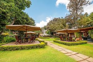 a patio with tables and umbrellas in a yard at Elewana Arusha Coffee Lodge in Arusha