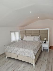 ein weißes Schlafzimmer mit einem großen Bett und Holzboden in der Unterkunft Sea side apartment in Kotor