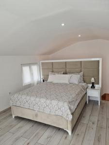a white bedroom with a large bed and a wooden floor at Sea side apartment in Kotor