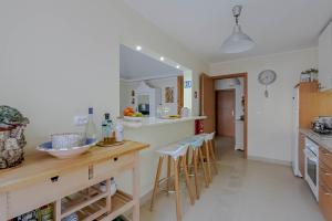a kitchen with a counter and bar with stools at Penthouse Dali - Cabanas Beach Club in Cabanas de Tavira
