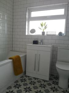 a bathroom with a sink and a toilet and a window at The Mila - Ayr Racecourse - Coorie Doon Stays in Ayr +14 photos