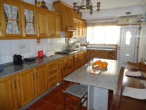 a kitchen with wooden cabinets and a table with fruit on it at Alojamento Poço do Barro in Lodões
