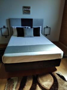 - un grand lit dans une chambre avec deux lampes dans l'établissement Leiria Village casa bungalow, à Leiria