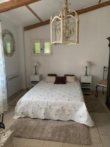 1 dormitorio con cama blanca y lámpara de araña en le mas des roses 1884 en Vence