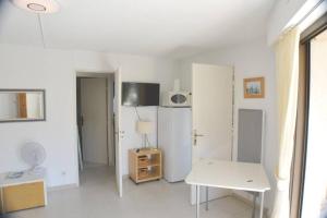ein weißes Wohnzimmer mit einem weißen Tisch und einem Zimmer in der Unterkunft BEL APPARTEMENT 2 PIECES A 200m DES PLAGES in Cavalaire-sur-Mer