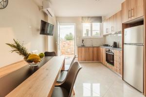 a kitchen with a wooden table with chairs and a refrigerator at Kelly's Sunset Apartment 1 Κalamata in Almirón