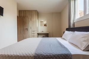 een slaapkamer met een bed met witte lakens en een raam bij Kelly's Sunset Apartment 1 Κalamata in Almirón
