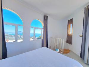 a bedroom with a white bed and two windows at Catalejo chalet casa rural 18 plazas in Águilas