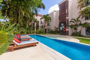 a swimming pool with two lounge chairs next to a building at Via Tendenza Condos in Playa del Carmen
