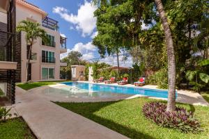 a swimming pool in front of a house with palm trees at Via Tendenza Condos in Playa del Carmen