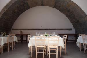 a dining room with white tables and chairs at Il Melograno in San Leonardello