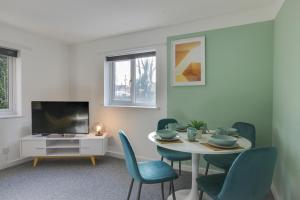 ein Wohnzimmer mit einem Tisch und Stühlen sowie einem TV in der Unterkunft George Suite - Free Parking and WiFi in Chelmsford