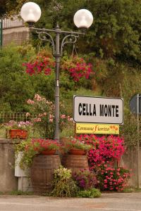 a street sign on a light pole with flowers at Benvenuti Altrove in Cella Monte