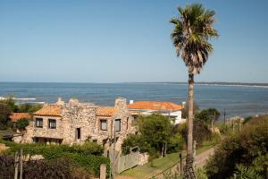 a house with a palm tree in front of the ocean at Posada Paradiso in José Ignacio