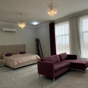 Dormitorio con sofá, cama y lámparas de araña en The Palace Chalet en Salalah