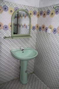een badkamer met een groene wastafel en een spiegel bij Batti Relax Point in Batticaloa