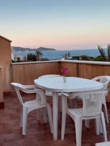 una mesa blanca y sillas en un balcón con vistas al océano en Casa di Jacu en Favignana
