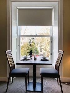 a table with two chairs in front of a window at The Craibstone Suites in Aberdeen