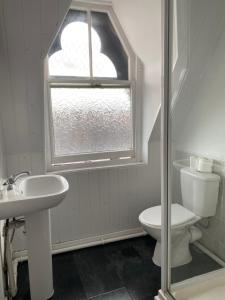 a bathroom with a toilet and a sink and a window at Park View Hotel and Guest House in Thatto Heath