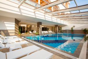 an indoor swimming pool with white chairs and a swimming pool at Orange Palace Side - All Inclusive in Side