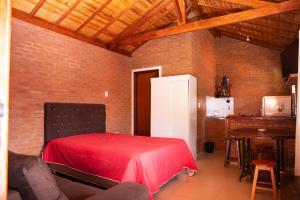 a room with a red bed with a table and a kitchen at Chale com lazer completo em Lima Duarte MG in Conceição da Ibitipoca