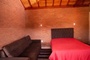 a bed and a couch in a room with a brick wall at Chale com lazer completo em Lima Duarte MG in Conceição da Ibitipoca