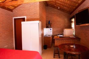 a small kitchen with a table and a white refrigerator at Chale com lazer completo em Lima Duarte MG in Conceição da Ibitipoca