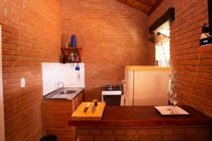 a kitchen with a brick wall and a refrigerator at Chale com lazer completo em Lima Duarte MG in Conceição da Ibitipoca